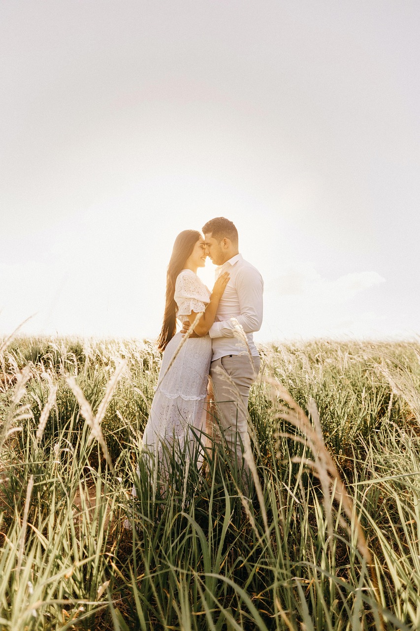 Backlit photo of a couple standing close together in a sunlit field