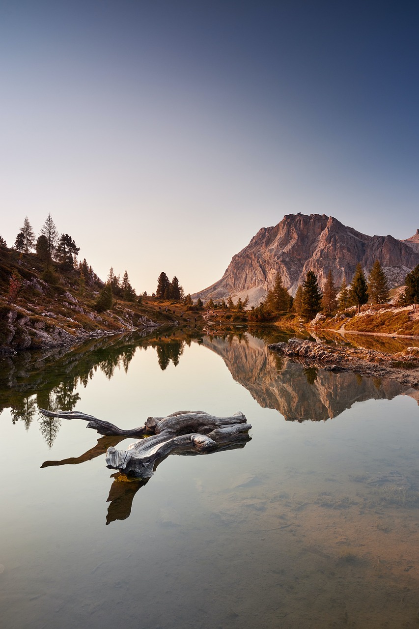 Photo of a still mountain lake reflecting a peak and larch trees